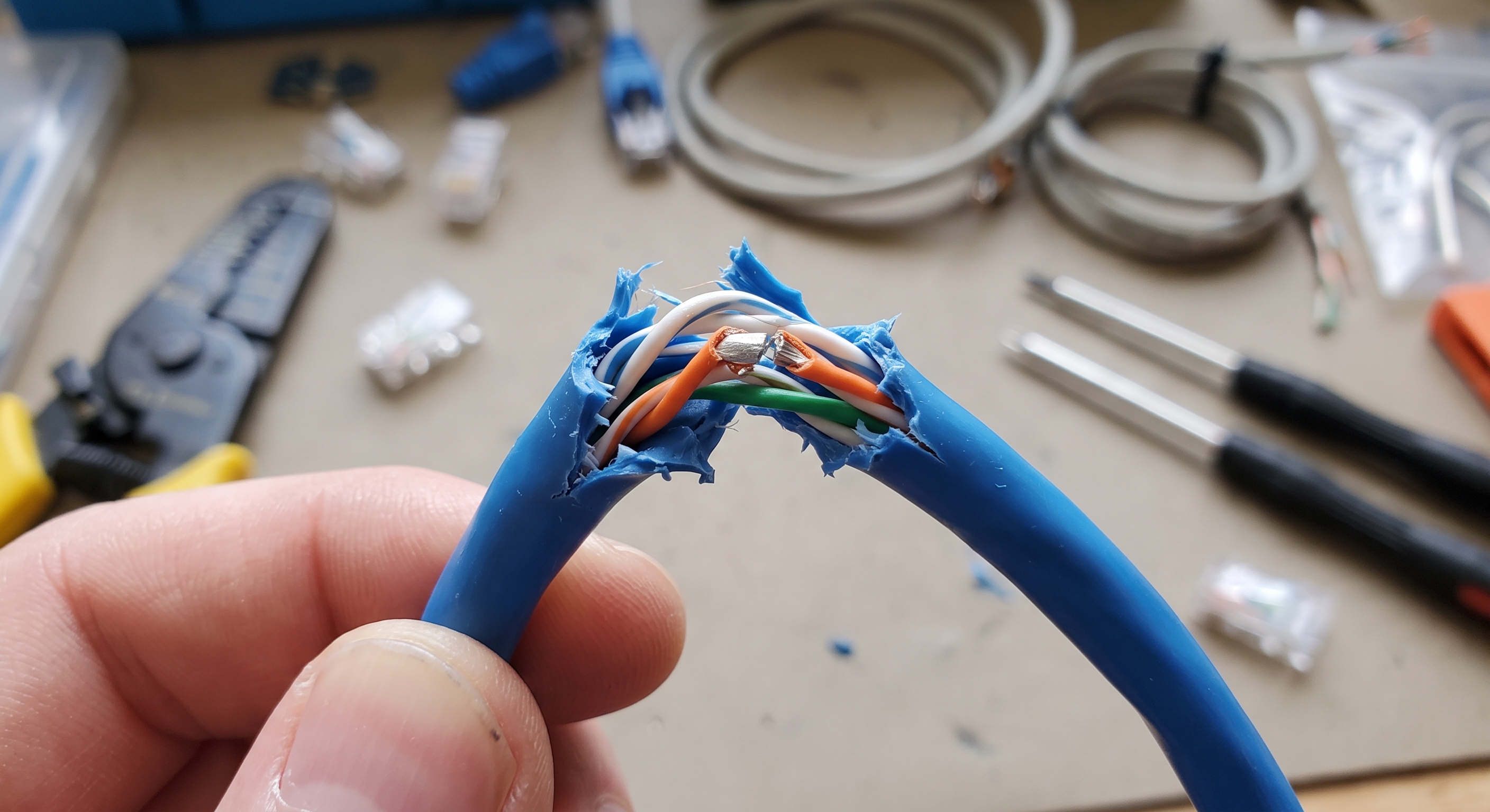 Cable de red doblado con el hilo del par naranja partido y la funda intacta